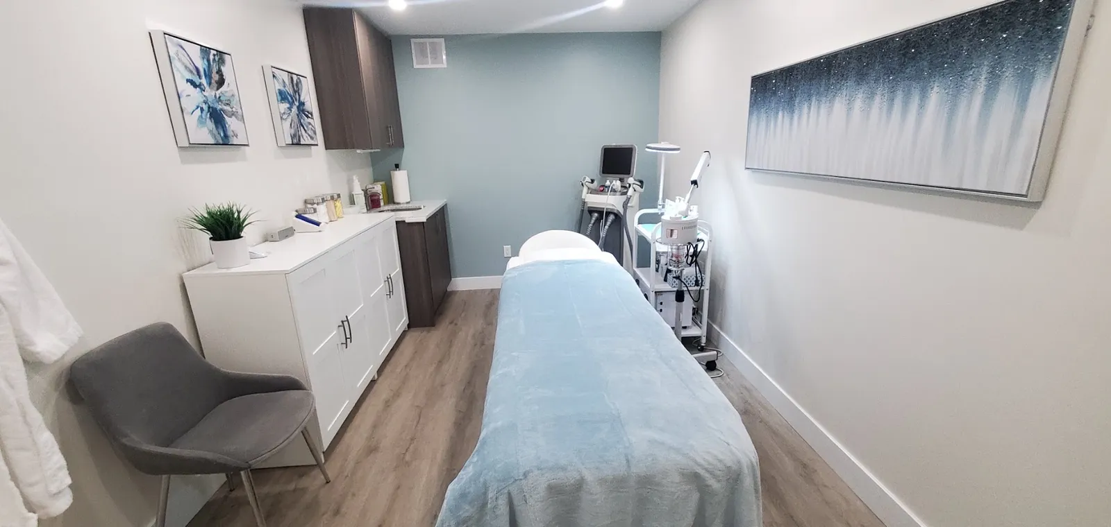 A treatment room at Skinnovation, with a treatment bed and artwork